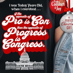 May include: Black t-shirt with a white and red graphic. The graphic includes text that reads "i was Today Years Old, when i overstood... if the opposite of Pro is Con then the opposite of Progress is Congress." A Capitol building illustration is at the bottom.