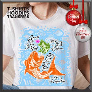 Pu&ograve; includere: T-shirt bianca con una grafica di pesce colorata e il testo "Small fish have big fish" e "Big fish have bigger fish". La maglietta ha anche il testo "and so on ad infinitum".