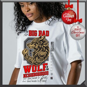 Puede incluir: Camiseta blanca con un gr&aacute;fico de un lobo con corona y brazo musculoso. El texto dice "BIG BAD WOLF IN THE NEIGHBORHOOD" en rojo. La camiseta tambi&eacute;n tiene el texto "not bad mean'n Bad, but bad mean'n Good".