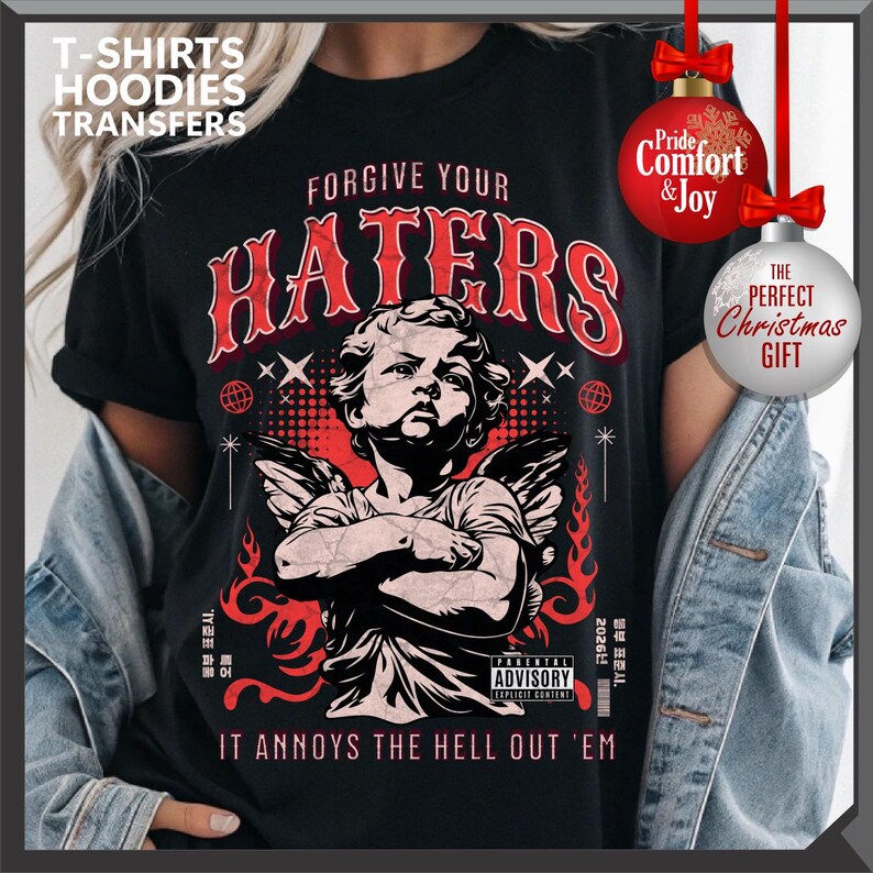 May include: Black t-shirt with a red graphic featuring an angel and the text "FORGIVE YOUR HATERS." Additional text includes "IT ANNOYS THE HELL OUT 'EM" and "PARENTAL ADVISORY EXPLICIT CONTENT." The shirt is a perfect Christmas gift.