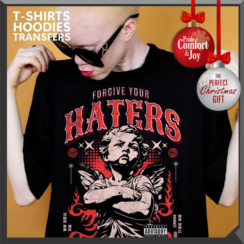 May include: Black t-shirt with the text "FORGIVE YOUR HATERS" in red, featuring an angel graphic. The shirt also has the text "T-SHIRTS HOODIES TRANSFERS" and "ADVISORY EXPLICIT CONTENT". Decorative Christmas ornaments are also visible.