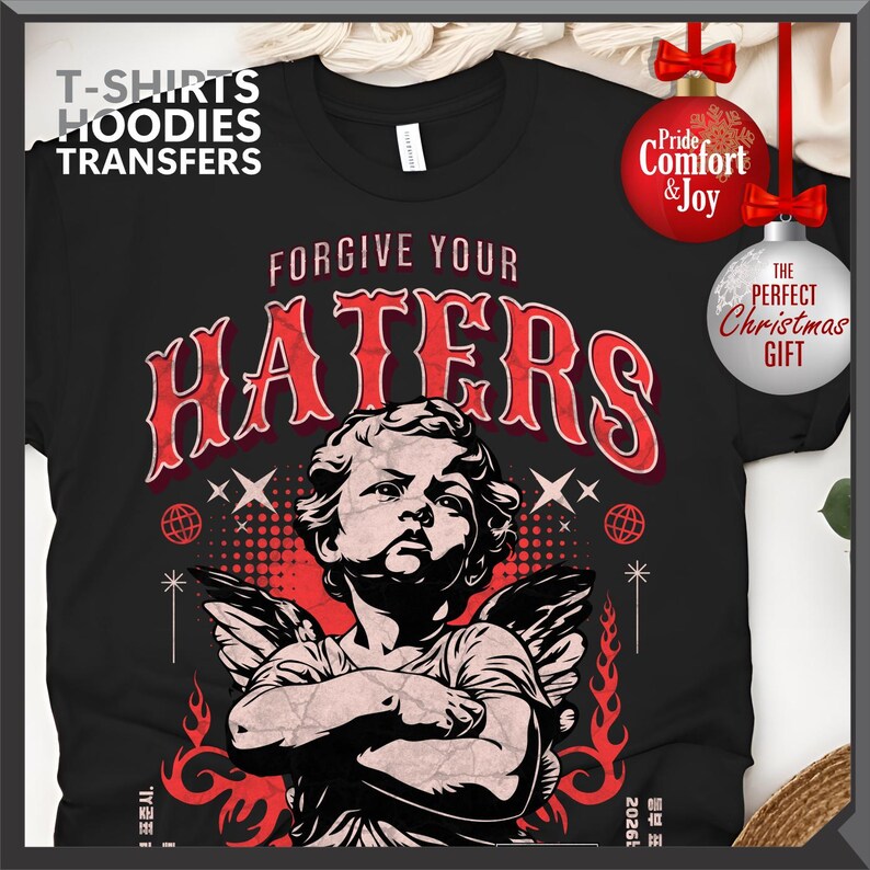 May include: Black t-shirt with a graphic featuring an angel and the text "FORGIVE YOUR HATERS." The design includes red accents and decorative elements. The shirt also has the text "T-SHIRTS HOODIES TRANSFERS."