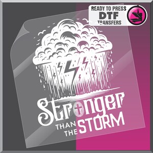 K&ouml;nnte beinhalten: Ein druckfertiger DTF-Transfer mit einer wei&szlig;en Illustration einer Gewitterwolke, Regen und Blitzen. Der Text "Stronger Than The Storm" steht darunter, mit einem Kreuzsymbol. Der Transfer befindet sich auf einer transparenten Folie.