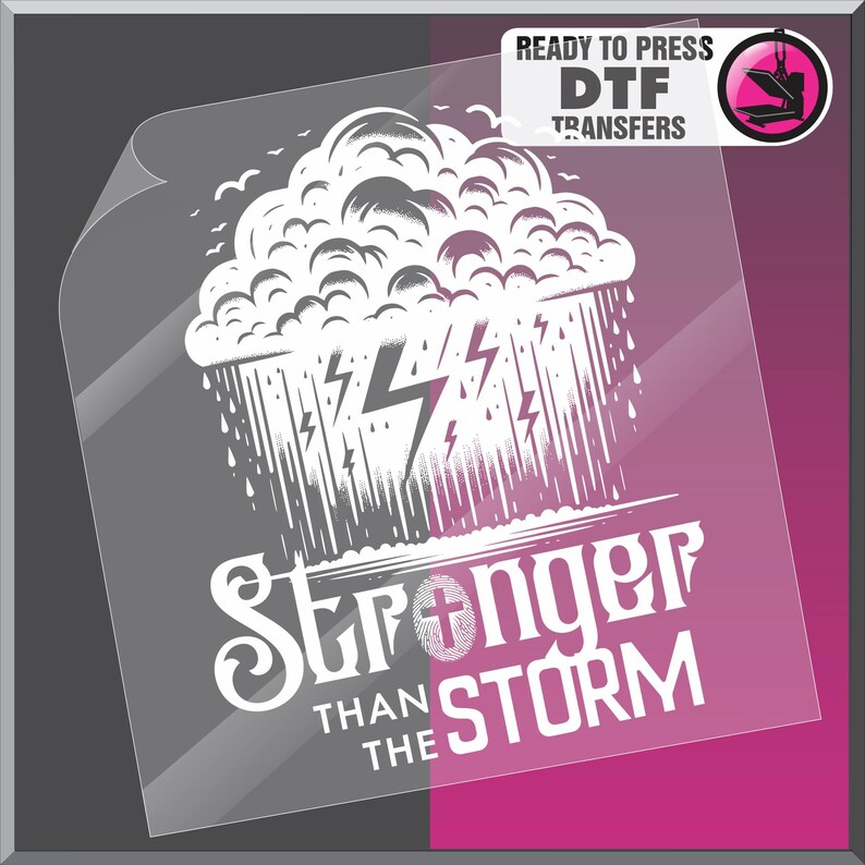 K&ouml;nnte beinhalten: Ein druckfertiger DTF-Transfer mit einer wei&szlig;en Illustration einer Gewitterwolke, Regen und Blitzen. Der Text "Stronger Than The Storm" steht darunter, mit einem Kreuzsymbol. Der Transfer befindet sich auf einer transparenten Folie.