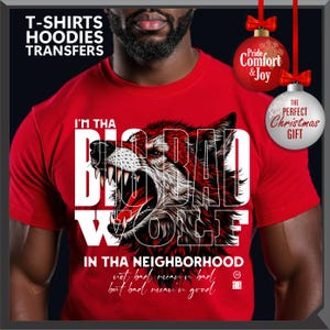 Op de afbeelding: Rood t-shirt met een afbeelding van een grommende wolf en de tekst "I'M THA BIG BAD WOLF IN THA NEIGHBORHOOD". Het shirt heeft ook de tekst "not bad mean'n bad but bad mean'n good". De afbeelding bevat kerstversieringen.