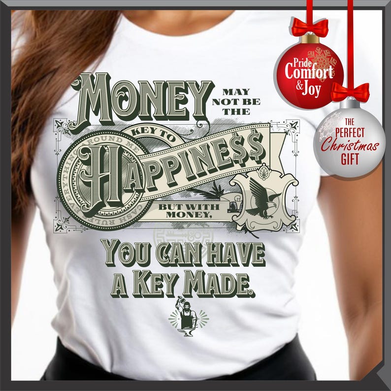 Pu&ograve; includere: T-shirt bianca con un design grafico con le parole "I soldi potrebbero non essere la chiave della felicit&agrave;, ma con i soldi, puoi farti fare una chiave". Il design include immagini di banconote e una piccola illustrazione di una persona che lavora in una fucina.