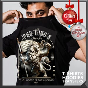 May include: Black t-shirt with a detailed lion illustration holding a flag, and the text "THE LION'S Story is Told" and "THE HUNTER IS THE WARRIOR". The design is framed and suitable for t-shirts, hoodies, and transfers. Includes Christmas gift baubles.