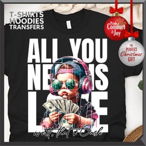 Puede incluir: Camiseta negra con un gr&aacute;fico de un ni&ntilde;o con gafas de sol y auriculares, sosteniendo dinero. El texto "ALL YOU NEED IS LOVE" est&aacute; impreso en letras blancas. La frase "well, that & Cash" est&aacute; escrita en la parte inferior.