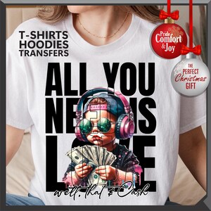 Puede incluir: Camiseta blanca con un gr&aacute;fico de un ni&ntilde;o con auriculares y gafas de sol, sosteniendo dinero. El texto "ALL YOU NEED IS LOVE" est&aacute; encima del ni&ntilde;o, con "well, that's cash" debajo. La camiseta tambi&eacute;n tiene impreso "T-SHIRTS HOODIES TRANSFERS".