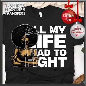 Może przedstawiać: Czarna koszulka z grafiką kobiety z afro i białym napisem "ALL MY LIFE HAD TO FIGHT". Koszulka ma r&oacute;wnież napis "T-SHIRTS HOODIES TRANSFERS" u g&oacute;ry.