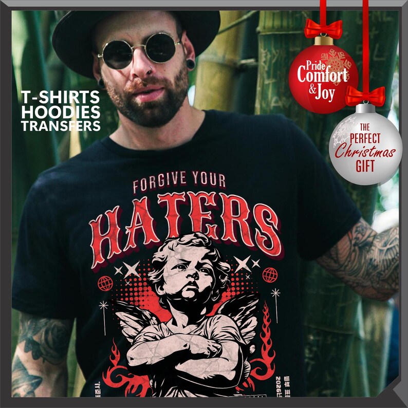 May include: Black t-shirt with the text "FORGIVE YOUR HATERS" in red, featuring an illustration of an angel. The image also includes text that says "T-SHIRTS HOODIES TRANSFERS". Two Christmas ornaments are also visible, one with the text "Pride Comfort & Joy" and the other with the text "THE PERFECT CHRISTMAS GIFT".