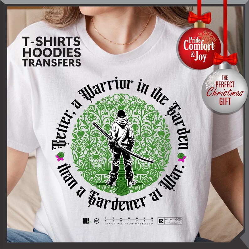 May include: White t-shirt with a graphic featuring a figure with a sword inside a green floral design. Text reads "Better, a Warrior in the Garden than a Gardener at War." Includes text "T-SHIRTS HOODIES TRANSFERS".