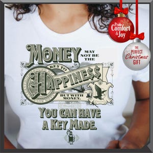 Pu&ograve; includere: T-shirt bianca con un design grafico verde e beige, con le parole "I soldi potrebbero non essere la chiave della felicit&agrave;, ma con i soldi, puoi farti fare una chiave." Include decorazioni natalizie.