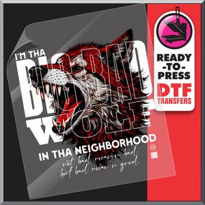 Op de afbeelding: Een DTF-transfer met een grommende wolf met rode en witte vacht, en de tekst "I'M THA BAD WOLF IN THA NEIGHBORHOOD". Het ontwerp bevat de zin "not bad mean'n bad but bad mean'n good". Een label "Ready-to-Press DTF Transfers" is ook zichtbaar.