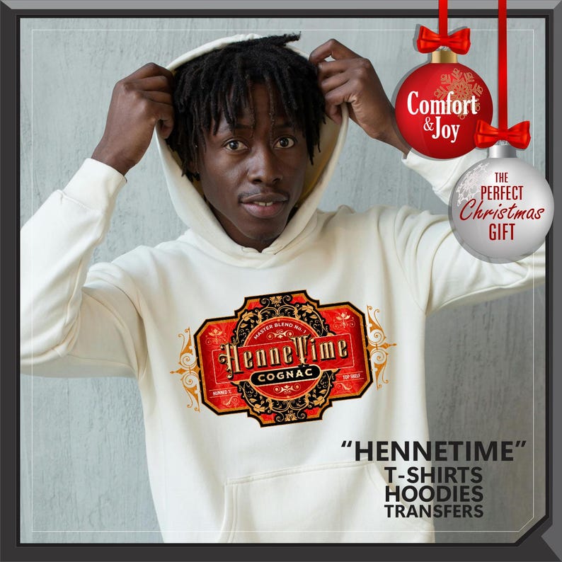 May include: A cream-colored hoodie with a cognac label design. The label is red and gold with the words "Henne Time Cognac." The text "HENNETIME" and product types are printed at the bottom. Christmas ornaments hang in the background.