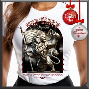 May include: White t-shirt with a detailed illustration of a muscular lion holding a flag. The design includes the text "The Lion's Story is Told" and "The Hunter is the Warrior". Christmas ornaments with text are also visible.