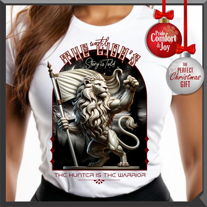 May include: White t-shirt with a detailed illustration of a muscular lion holding a flag. The design includes the text "The Lion's Story is Told" and "The Hunter is the Warrior". Christmas ornaments with text are also visible.