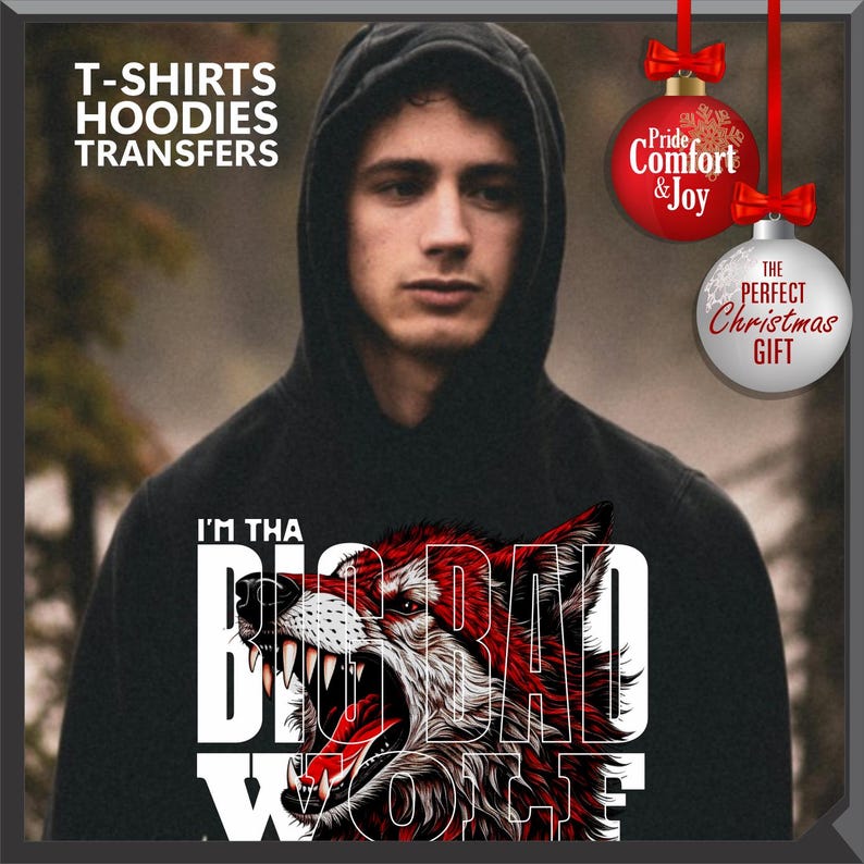 Op de afbeelding: Zwarte hoodie met een afbeelding van een grommende wolf en de tekst "I'M THA BIG BAD WOLF". De afbeelding bevat ook de tekst "T-SHIRTS HOODIES TRANSFERS". Twee kerstballen zijn ook zichtbaar, een rode en een zilveren.