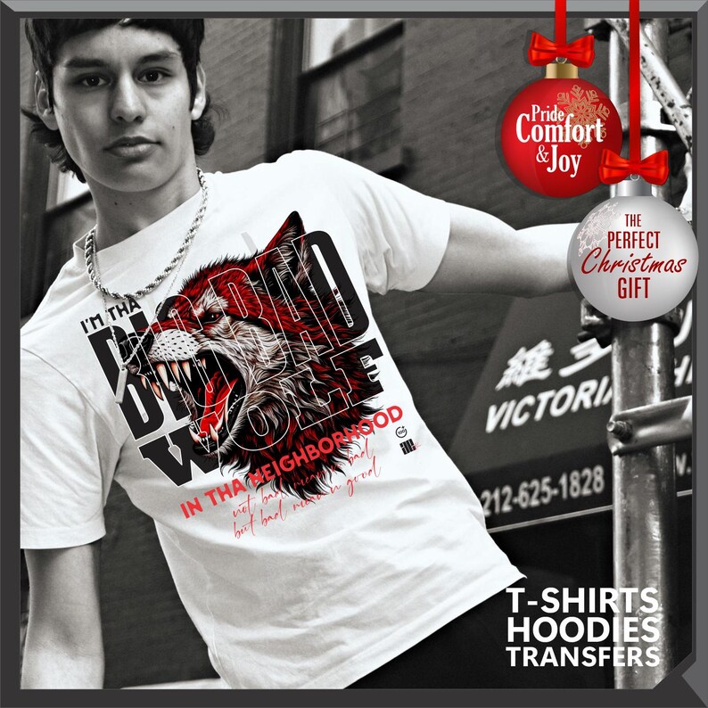 Op de afbeelding: Wit T-shirt met een afbeelding van een grommende wolf in rood en zwart. De tekst op het shirt luidt "I'M THA BAD WOLF" en "IN THA NEIGHBORHOOD". De afbeelding bevat ook de tekst "T-SHIRTS HOODIES TRANSFERS".