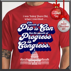 May include: Red t-shirt with white and blue text that reads "i was Today Years Old, when i overstood... if the opposite of Pro is Con then the opposite of Progress is Congress." Includes a graphic of the U.S. Capitol.
