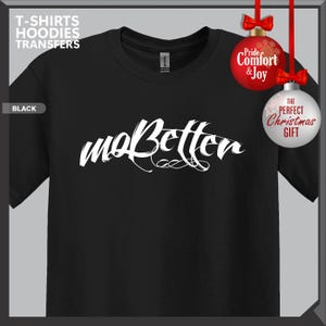 May include: Black t-shirt with the white cursive text "maBetter". The shirt has a crew neck and short sleeves. The words "T-SHIRTS HOODIES TRANSFERS" are in the upper left corner. The words "Pride Comfort & Joy" and "THE PERFECT Christmas GIFT" are also visible.