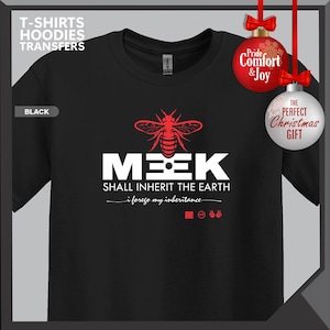 May include: Black t-shirt with a red bee graphic above the word "MEEK" in white, and the phrase "SHALL INHERIT THE EARTH". The shirt also has the text "i forego my inheritance". Christmas ornaments are in the background.