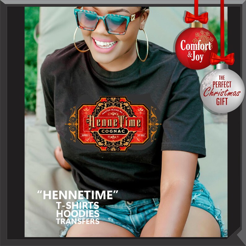 May include: Black t-shirt with a HenneTime Cognac label design in red, gold, and black. The image includes text that says "Comfort & Joy" and "The Perfect Christmas Gift". Additional text at the bottom says "HENNETIME" T-SHIRTS HOODIES TRANSFERS.