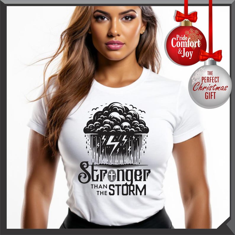 K&ouml;nnte beinhalten: Wei&szlig;es T-Shirt mit einer schwarz-wei&szlig;en Grafik einer Gewitterwolke, Blitzen und dem Text "Stronger Than The Storm". Das Shirt hat kurze &Auml;rmel und einen Rundhalsausschnitt.