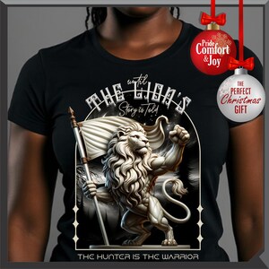 May include: Black t-shirt with a detailed illustration of a lion holding a flag, with the text "THE LION'S Story is Told" and "THE HUNTER IS THE WARRIOR". The design is in a white and grey colour scheme.