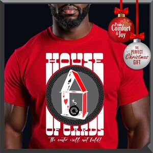 May include: Red t-shirt with a graphic of a house of cards design. The design includes playing cards, a bomb, and the text "HOUSE OF CARDS" and "The center will not hold!"