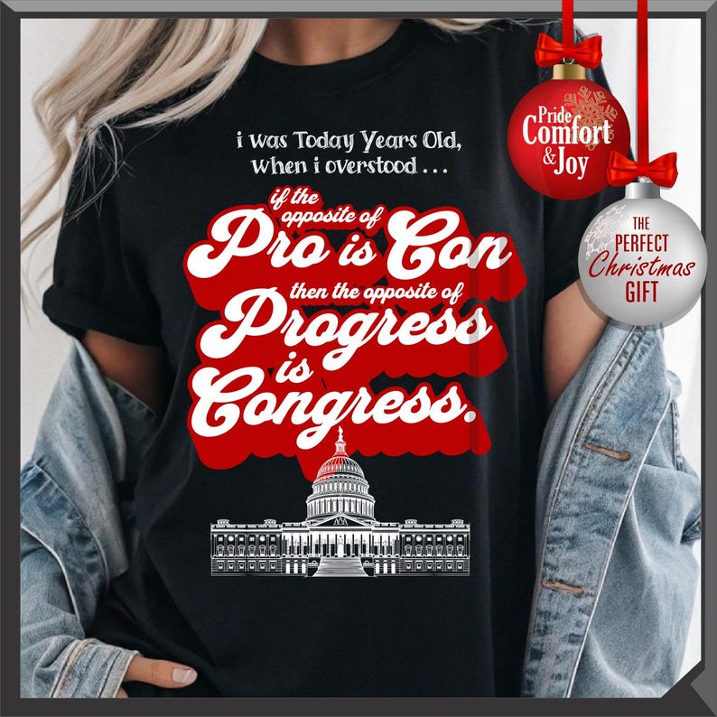 May include: Black t-shirt with a white and red graphic. The graphic includes text that reads "i was Today Years Old, when i overstood... if the opposite of Pro is Con then the opposite of Progress is Congress." A Capitol building illustration is at the bottom.