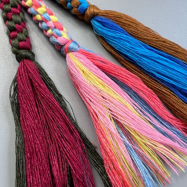 Puede incluir: Tres borlas trenzadas con hilos de colores. Las borlas est&aacute;n hechas de una variedad de colores, incluyendo verde, rojo, azul, amarillo y rosa.