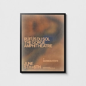 May include: A rectangular concert poster in a black frame featuring a blurred, abstract background of brown, orange, and dark blue tones. The text reads RÜFÜS DU SOL, THE GORGE AMPHITHEATRE, MARIBOU STATE, and JUNE 5TH+6TH with additional small text.