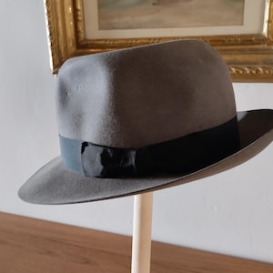 May include: A grey fedora hat with a black ribbon and a black bow.