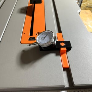 Peut inclure: Gros plan d'un indicateur de cadran fixé à une scie à table. L'indicateur de cadran sert à mesurer la précision de la coupe de la scie.