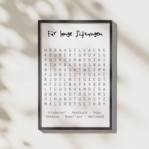May include: A black framed print with the text "F&uuml;r lange Sitzungen" in white. The print features a word search puzzle with the words "Klodeckel", "Handtuch", "Pups", "Shampoo", "Nagellack", and "Wattepad" listed below.