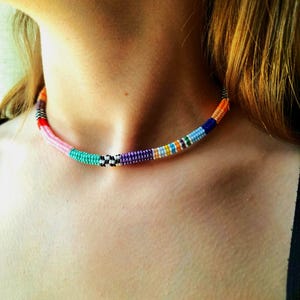 May include: A colorful beaded necklace with alternating patterns of black and white, pink, blue, purple, orange, yellow, and turquoise beads.