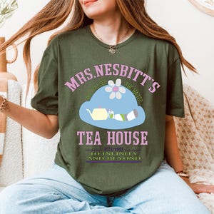 a woman sitting on a couch wearing a green shirt