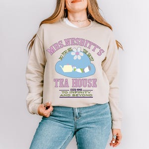 a woman wearing a sweatshirt with a tea house on it