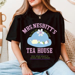 a woman sitting on a couch wearing a black t - shirt