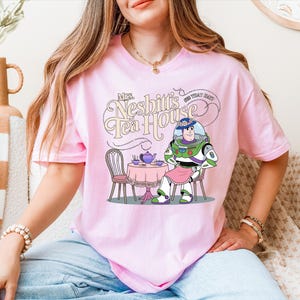 a woman sitting on a couch wearing a pink shirt