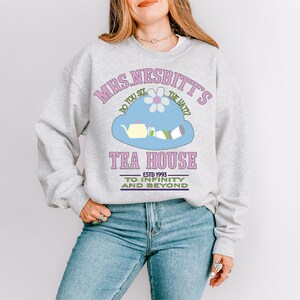 a woman wearing a sweatshirt with a tea house on it
