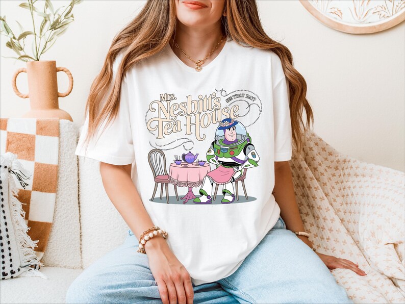 a woman sitting on a bed wearing a t - shirt with an image of a