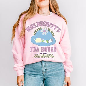 a woman wearing a pink sweatshirt and jeans