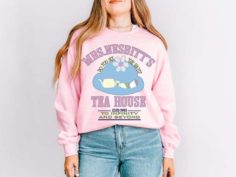 a woman wearing a pink sweatshirt and jeans