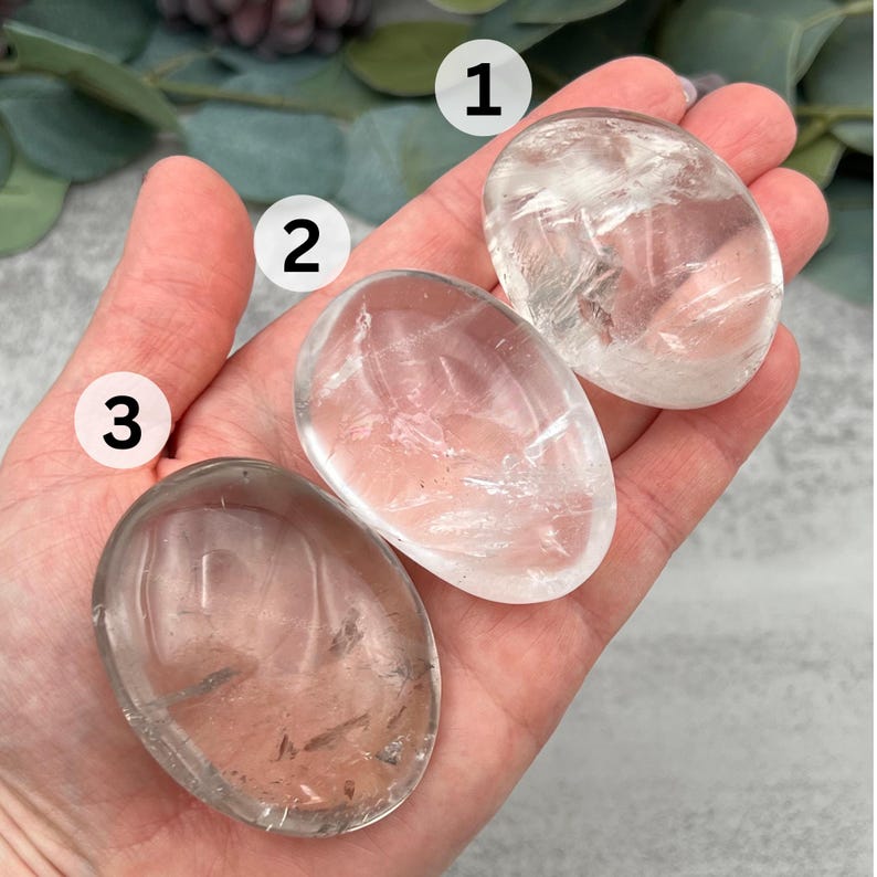 May include: Three clear quartz crystal stones, each with a different shape and size. The stones are smooth and polished, and they have a natural, translucent appearance.