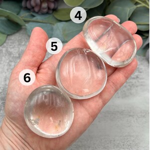 May include: Three clear quartz crystal coasters, each with a smooth, polished surface. The coasters are different sizes, with the largest being about 4 inches in diameter.