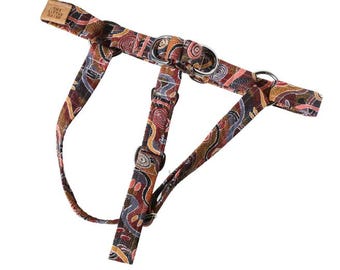 May include: A dog harness with a colorful, abstract pattern in shades of brown, red, and blue. The harness has metal rings and adjustable straps. The label reads "THE LITTLE DAISY".