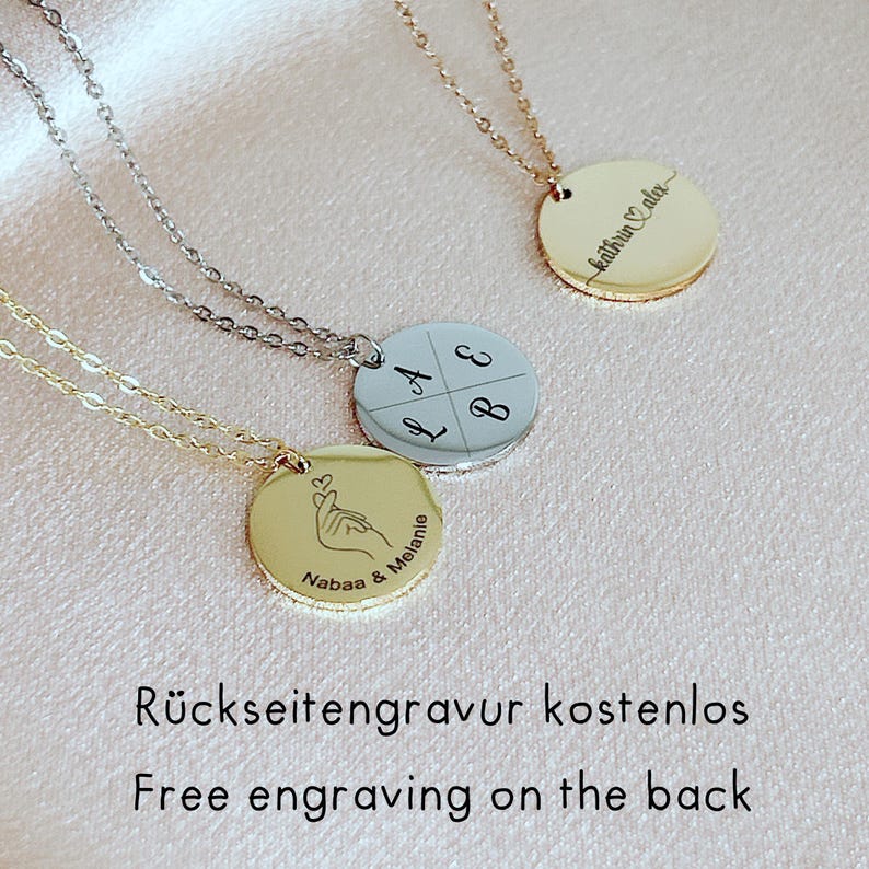 Peut inclure: Trois colliers &agrave; pendentifs circulaires avec des cha&icirc;nes fines. Un pendentif dor&eacute; pr&eacute;sente un geste de c&oelig;ur avec la main et le texte Nabaa & Melanie. Un pendentif argent&eacute; est divis&eacute; en quatre quadrants avec les lettres A, B, L, E. Un pendentif dor&eacute; porte le texte kathrin & alex.