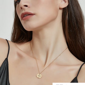 Peut inclure: Un collier dor&eacute; compos&eacute; d'une fine cha&icirc;ne et d'un petit pendentif circulaire. Le pendentif est grav&eacute; d'un motif floral d&eacute;licat aux lignes fines. Le collier repose sur le cou, mettant en valeur une finition m&eacute;tallique simple et polie.
